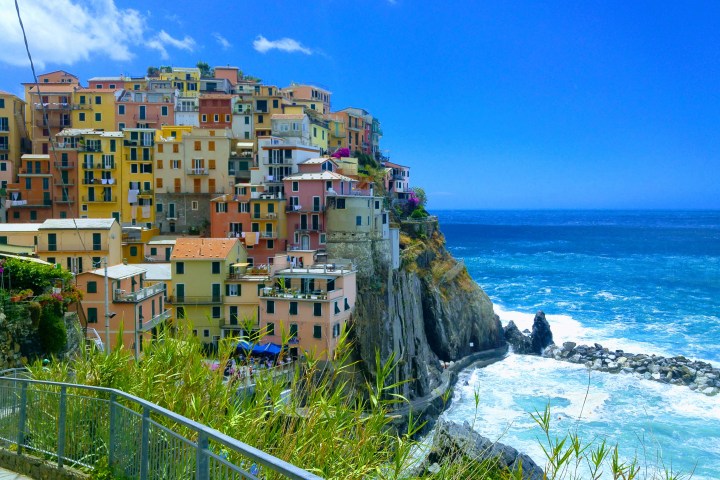 Colorful cliffside houses overlooking a blue ocean with a clear sky.