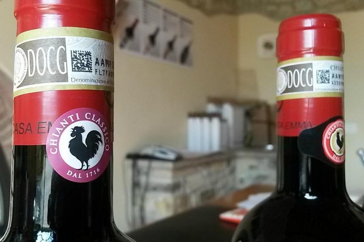Close-up of two Chianti Classico wine bottles with red seals and rooster labels, indoors.
