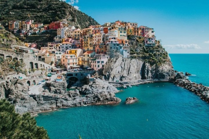 Colorful houses on cliffside overlooking a turquoise sea under a clear blue sky.