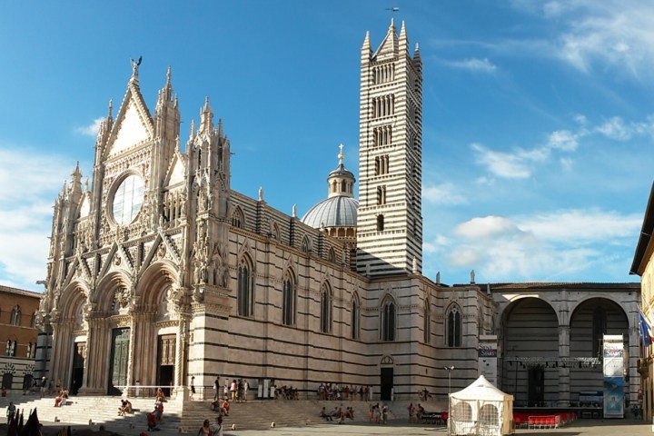 A Gothic cathedral with a striped bell tower under a blue sky.