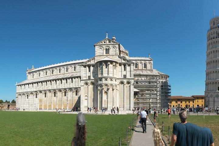The Leaning Tower of Pisa, cathedral, and baptistery under a clear blue sky.