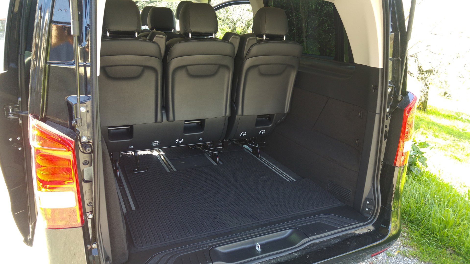 Open rear view of a black van with third row seats folded up.
